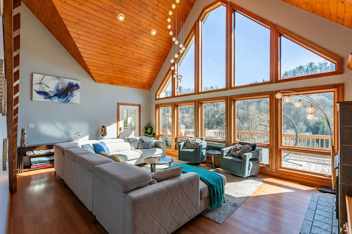 A comfortable seating area with modern fixtures and giant windows that offer panoramic views of the outdoors. The natural lighting and inviting atmosphere set the stage for family gatherings, quiet moments with a book, or relaxed conversations.