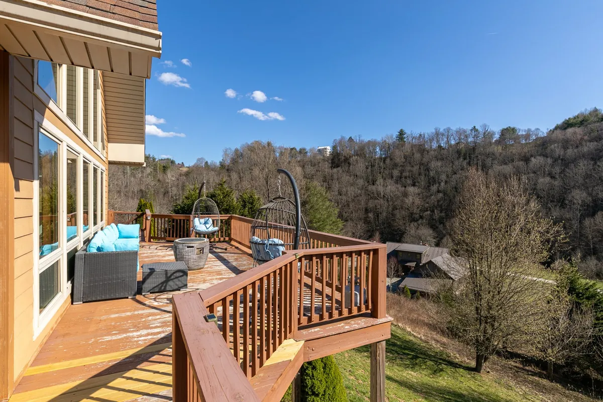 This image presents a comfortable outdoor seating area on the deck, complete with a hanging chair and cozy furnishings. The scene looks out to the mountain landscape, inviting guests to sit back, socialize, or take in the view. The relaxed atmosphere and ample seating reinforce the yard and deck as gathering spaces.