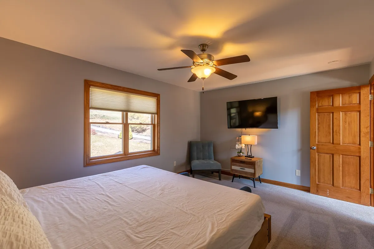 A cozy nook with a bed, window, television, chair, and lamp. It suggests a space for relaxing, watching TV, or curling up with a book—emphasizing comfort and flexibility, possibly used as extra sleeping quarters or a quiet hangout.