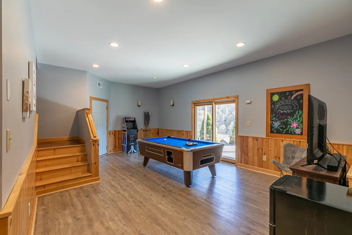 An inviting interior shot with a pool table, a large window providing ample natural light, and a chalkboard on the wall. The space feels casual and welcoming, suggesting both competitive fun and opportunities for creative expression or socializing.